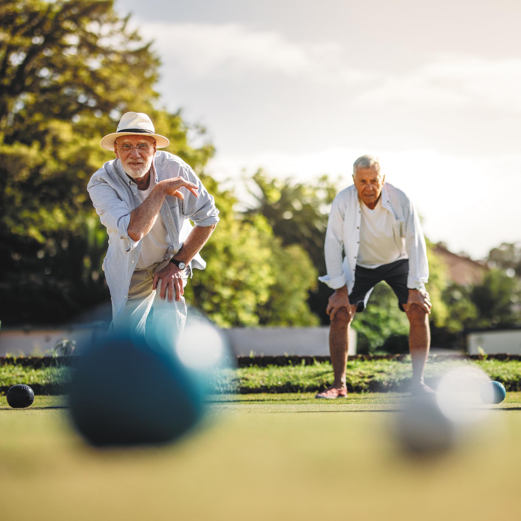 Senior man throwing a boules standing in position