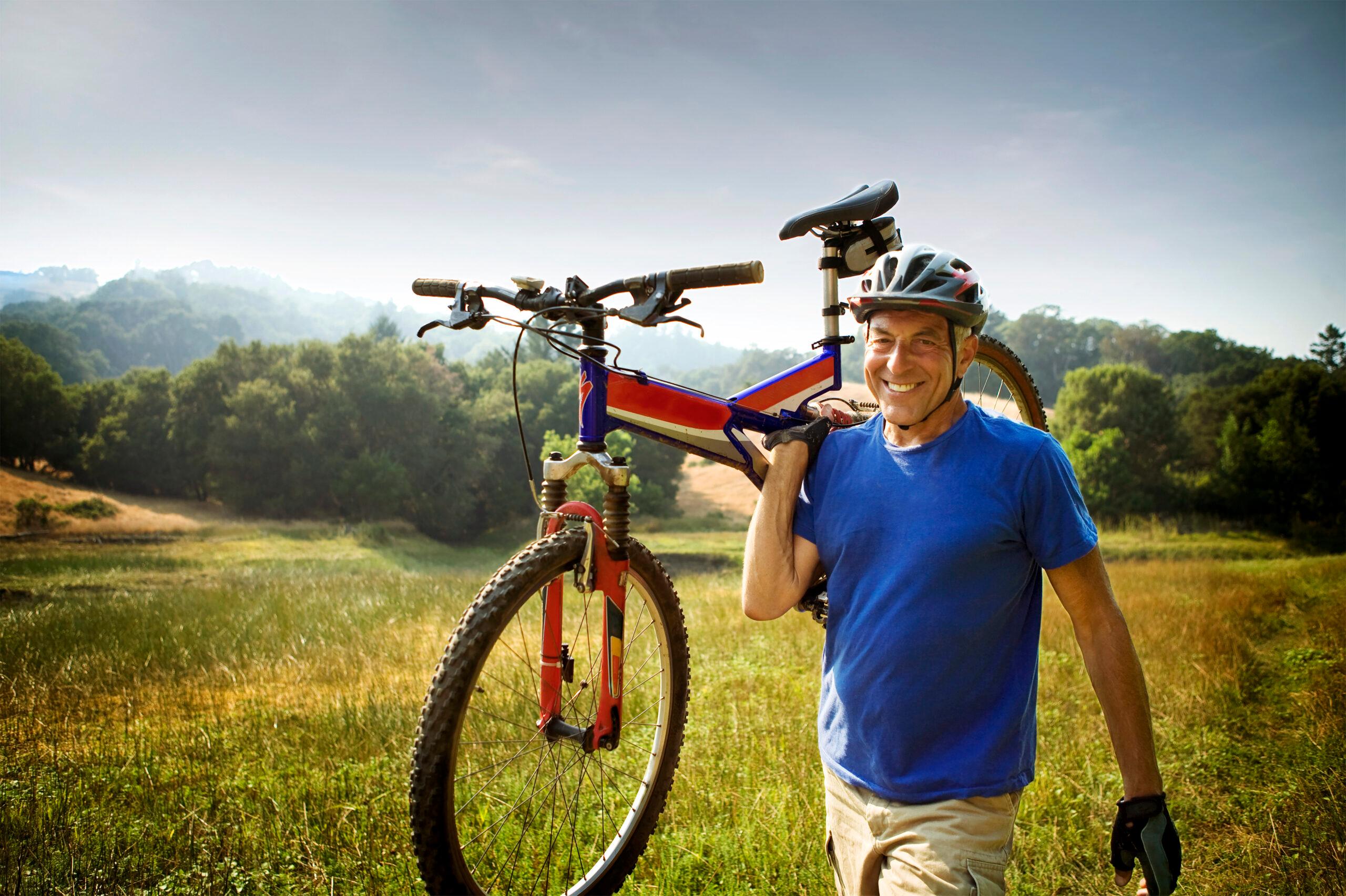 Senior man carries a mountain bike