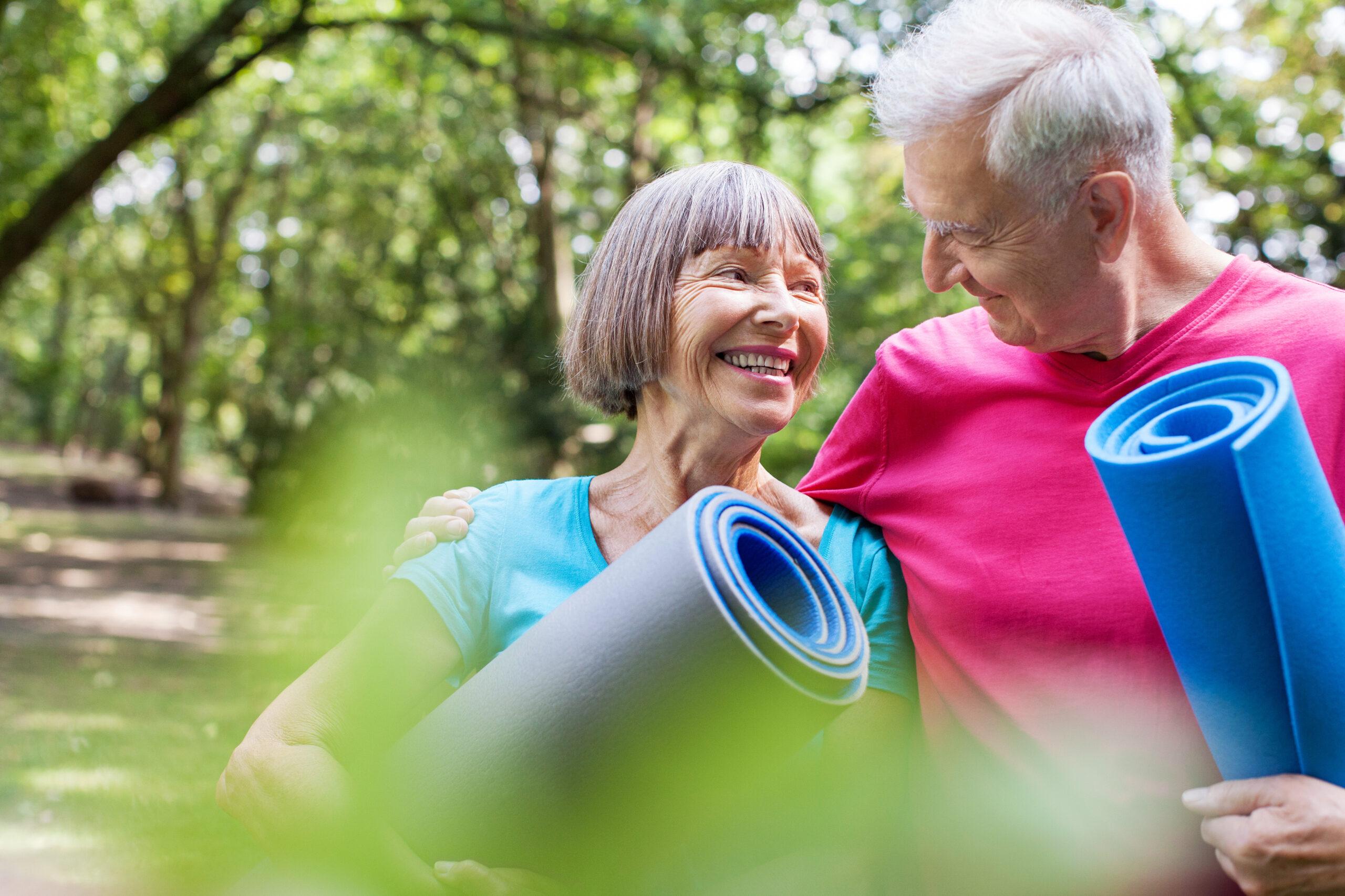 Healthy senior couple with yoga mat in the park