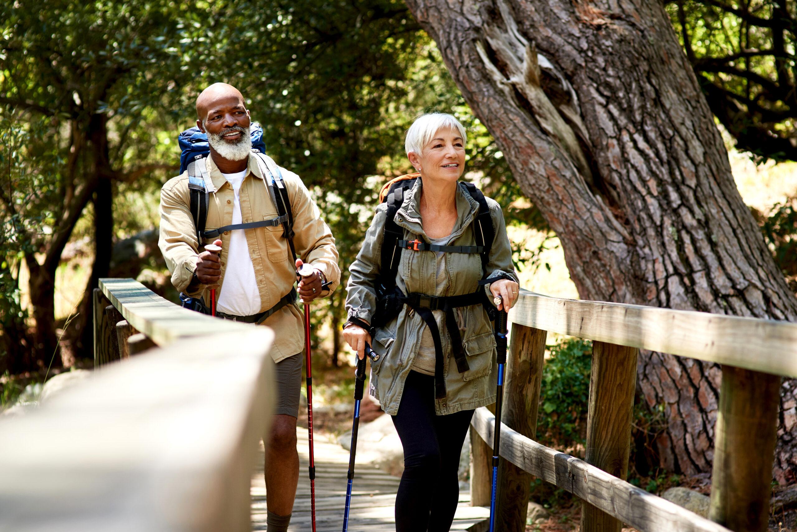 Hiking couple smiles as they cross a bridge