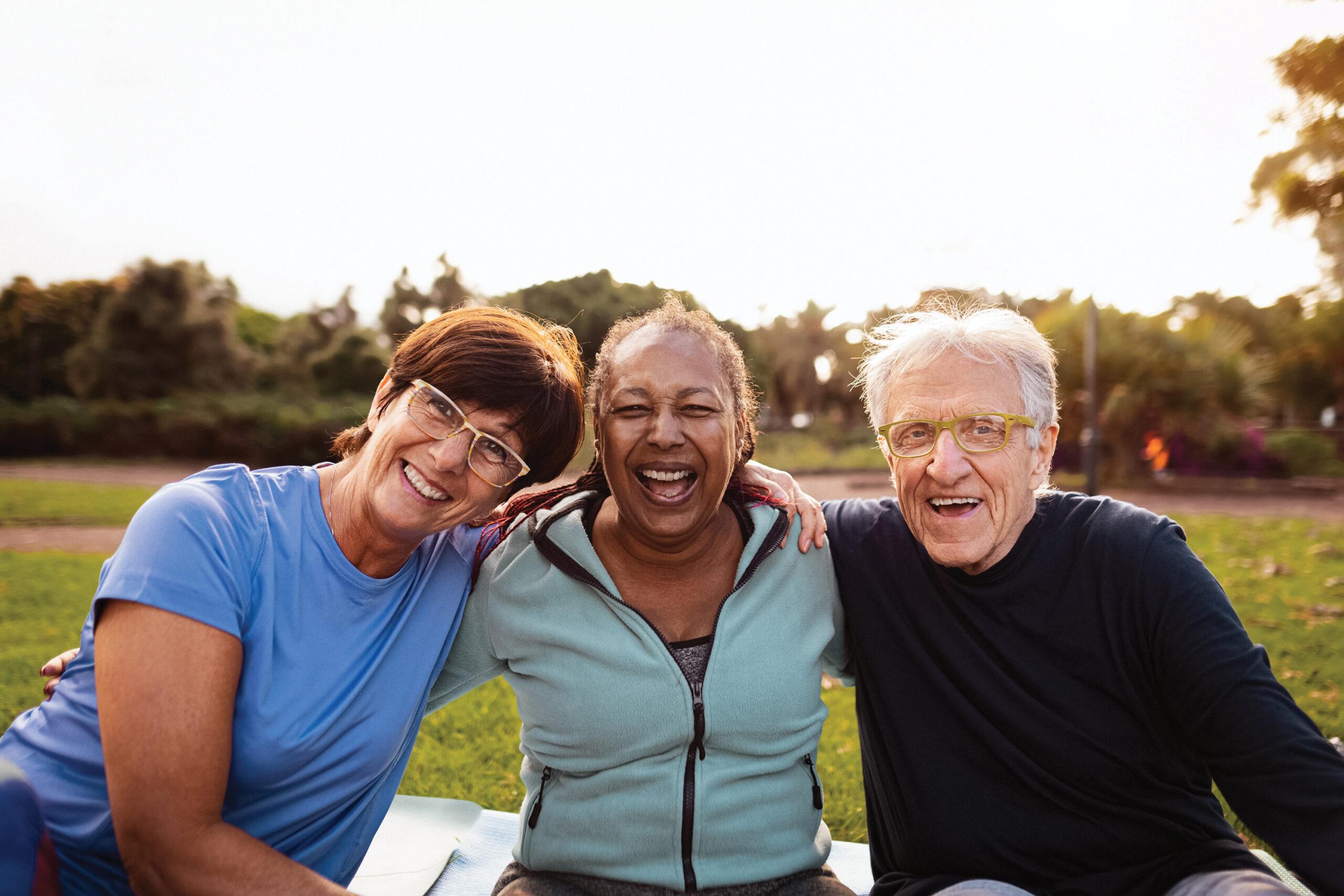 A group of three friends smiles outdoors